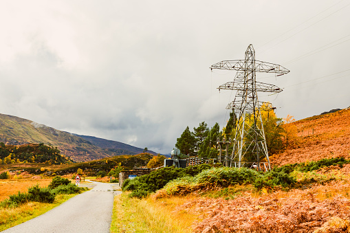 Deanie Power Station in the remote Glen Strathfarrar in the Scottish Highlands with pylon and power lines.  Autumn with golden ferns.  Copy space.  Horizontal.