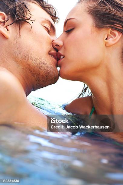매력적인 젊은 커플입니다 키스 In The Sea 커플에 대한 스톡 사진 및 기타 이미지 - 커플, 갈색 머리, 수영장-스포츠 경기장