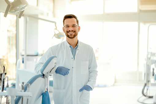 Portrait of a confident dentist in a medical office or clinic. Attractive bearded young man, modern male doctor or friendly medic in the workplace.