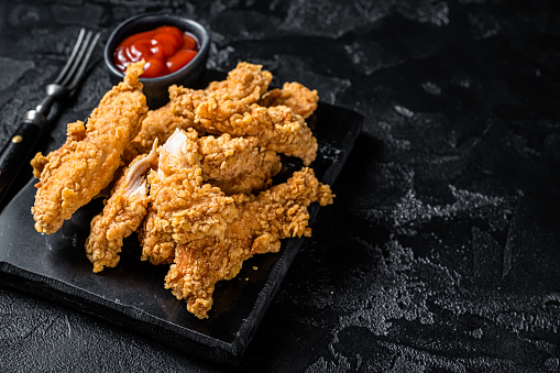 Breaded chicken strips  Fingers with  Ketchup. Black background. Top view. Copy space.
