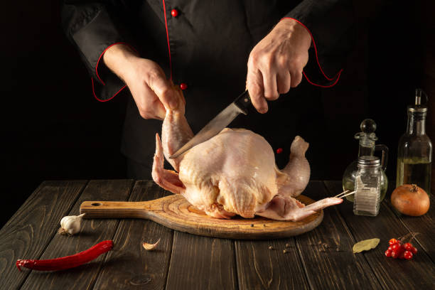 istock Professional chef cuts raw chicken with a knife in the kitchen. Cooking chicken for lunch. Grande cuisine 1443352946
