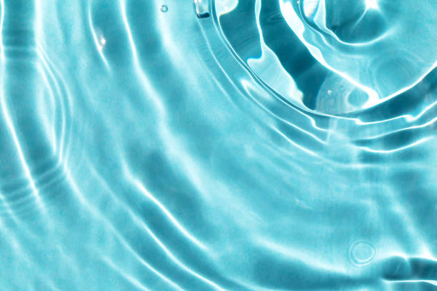Textured background of waves on light blue water with solar lightning Textured background of waves on light blue water with solar lightning. The concept of peace and relaxation. Close-up, selective focusing, defocusing water stock pictures, royalty-free photos & images
