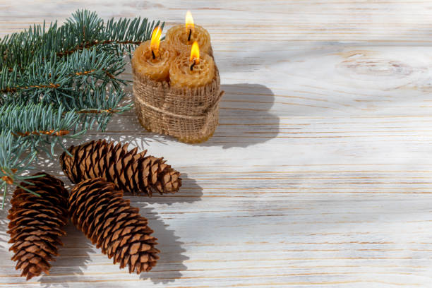 istock Fir branch, burning candles, cones on a white wooden background 1443353608