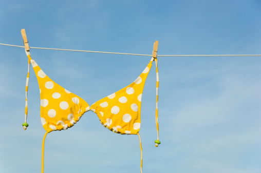 Yellow polka dot bikini hanging on clothesline against blue sky - with copy space