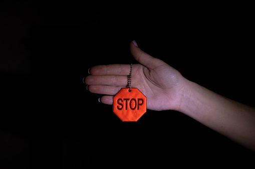 The girl holds in her hand a reflective keychain with the inscription stop in the dark, stop sign