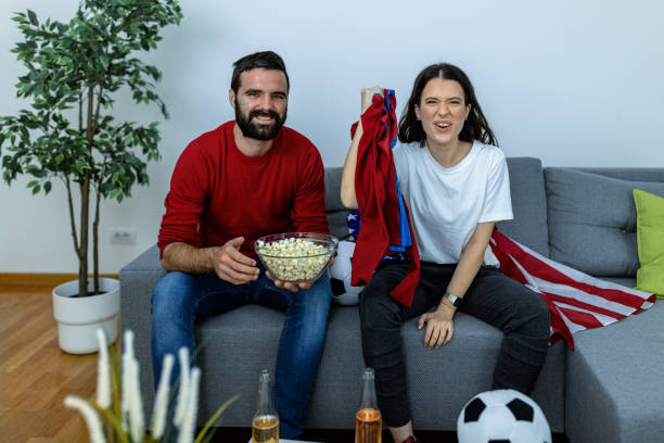 młody mężczyzna i jego dziewczyna oglądają mecz piłki nożnej. - sitting 20s adult american football zdjęcia i obrazy z banku zdjęć