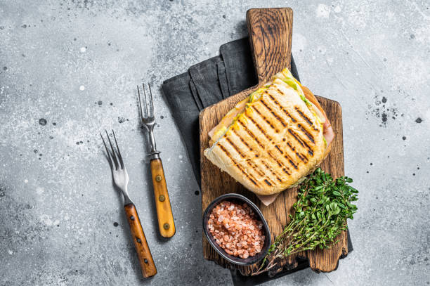 生ハムとチーズのトーストしたパニーニサンドイッチ。グレイの背景。平面図 - mozzarella tomato sandwich picnic ストックフォトと画像