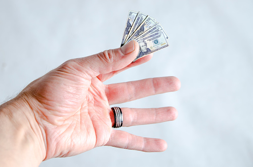 Hand holding tiny 20 dollar bills to represent loss of spending power on white background.
This is to represent shrinkflation, the fact that, to make more money, the manufacturers are reducing the package and keeping the same price of goods.
The consumers are then losing spending power.