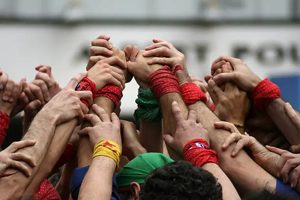 Several castellers (men) raising their hands and preparing to build a human tower, a catalan 'Castell'.
