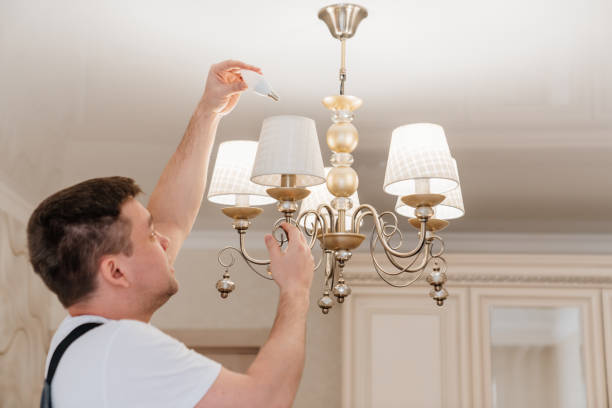 istock A male electrician changes the light bulbs in the ceiling light. 1443370546