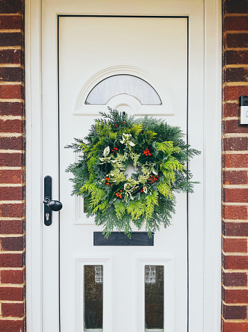 Fresh foraged Christmas wreath hanging on the front door of an English home