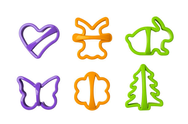 Multicolored cookie cutter set for homemade biscuit cutout. Cookie dough cutters in the shape of heart, butterfly, flower, rabbit and fir tree isolated on a white background. Baking concept.