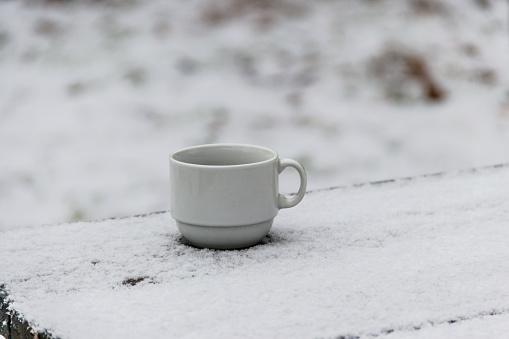 Cup of coffee on a snow covered table at winter