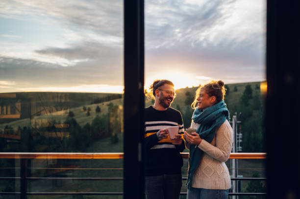 istock Young couple drinking coffee or tea while standing on their balcony at sunrise 1443381611