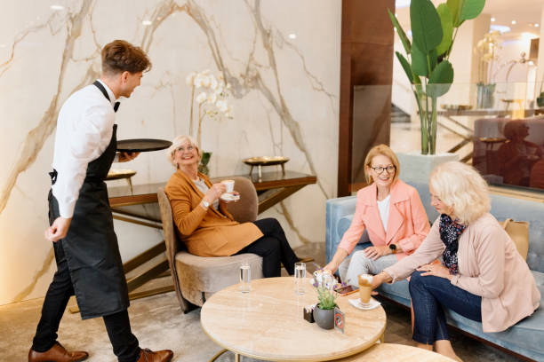 istock Friendly waiter serving senior ladies at a hotel cafe 1443389235