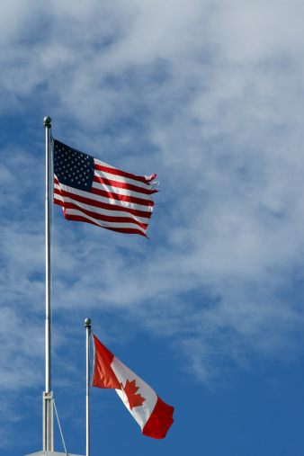 A US and Canadian flag with a nice blue background sky