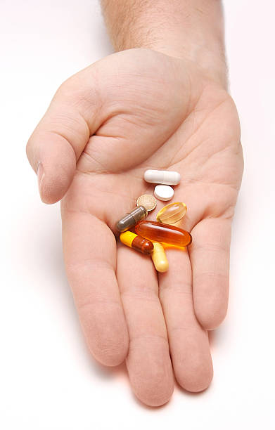 Hand outstretched with a pile of pills stock photo