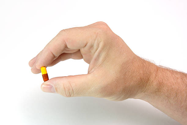 Hand holding two color pill stock photo