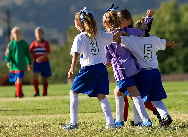 Four girls celebrate after a win playing soccer.