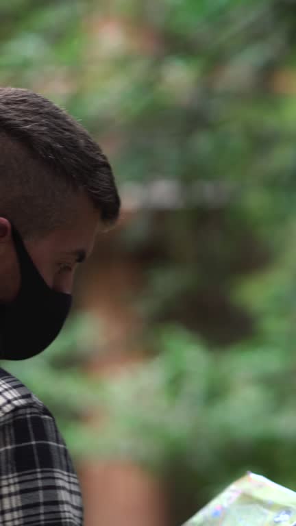 Man wearing face mask lost in the forest looking at a map