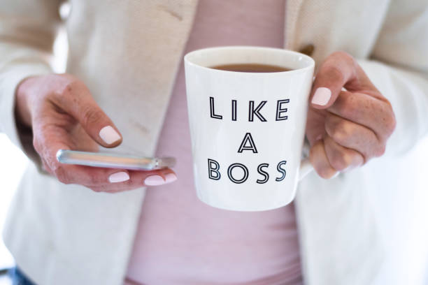 istock Business woman using mobile phone and holding cup that says Like a Boss 1443405775