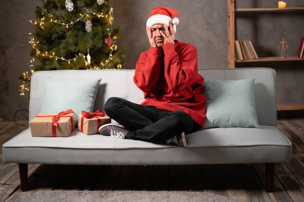 istock Young frustrated man having problems holding hands on face sitting at home financial troubles, depression on christmas eve 1443407101