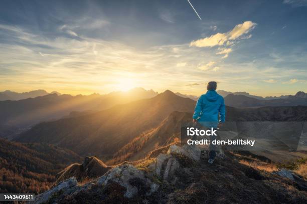 Man On Stone On The Hill And Beautiful Mountains In Haze At Colorful Sunset In Autumn Dolomites Italy Sporty Guy Mountain Ridges In Fog Orange Grass And Trees Blue Sky With Sun In Fall Hiking Stock Photo - Download Image Now