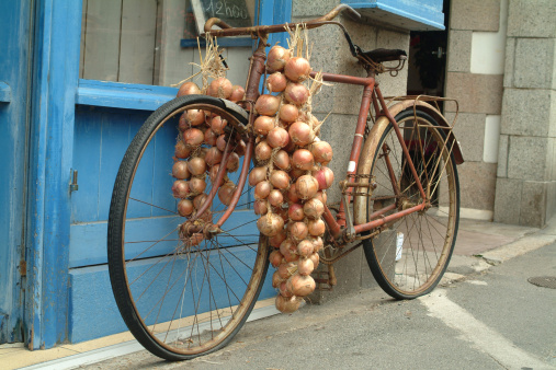 Bicycle with onions on it in the street in front of a blue door
