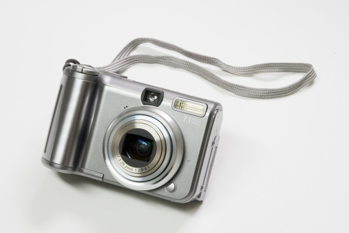 A Point-and-shoot digital camera complete with carrying strap.