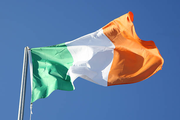 Irish flag blowing in the wind on blue sky stock photo