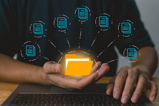 istock Businessman holding folder and document icon software, searching and managing files in online document databases for efficient archiving and company data. 1443418517