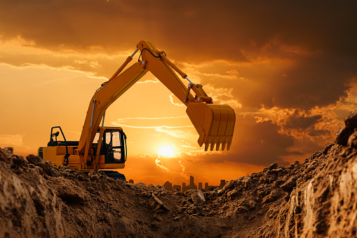 Excavators are digging the soil in the construction site on the  sunset  background in city