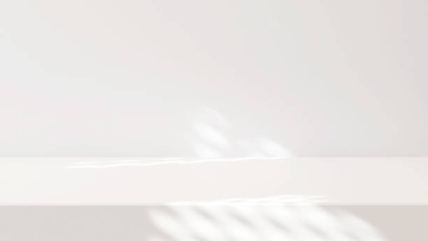 White blank tabletop or countertop in modern and minimal wall room with dappled sunlight and tree shadow from window