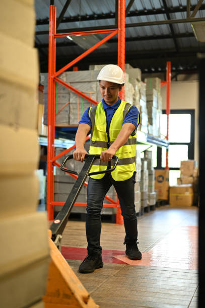istock Determined Asian male warehouse worker pulling the pallet truck, working in warehouse. 1443421819
