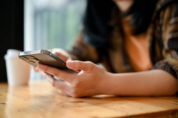 istock Female hands using her mobile phone while relaxing in the coffee shop. close-up image 1443421905