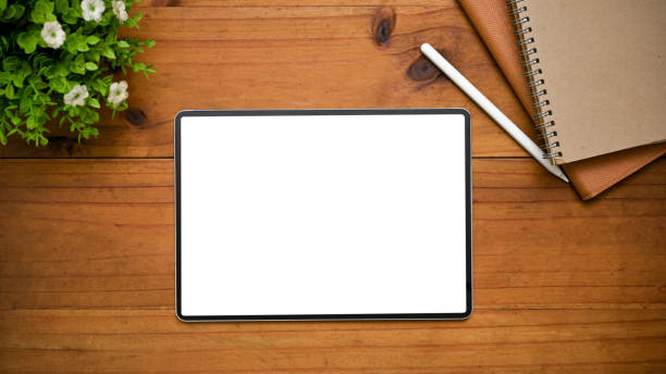 istock Digital tablet mockup is on a wooden tabletop background with decor. workspace top view 1443421939