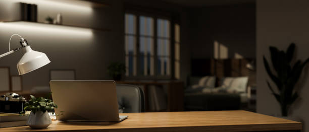 istock Minimalist home workspace at night with laptop, table lamp and copy space on wood table 1443422088