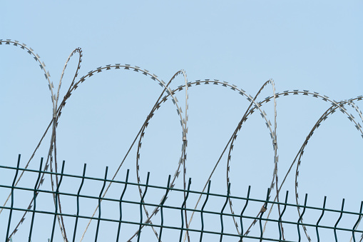 Barbed wire over a concrete fence, close-up, closed territory, military facility, prison
