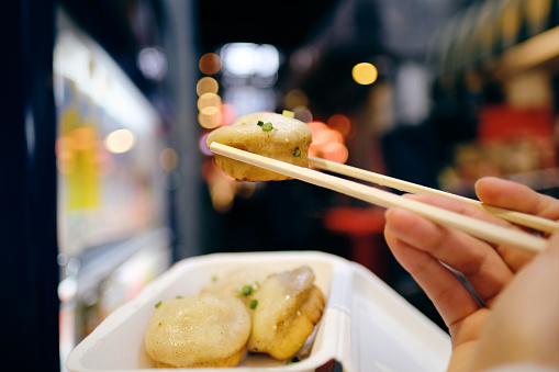 Woman eating take-out food on Izakaya street in Kichijoji, Tokyo, Japan