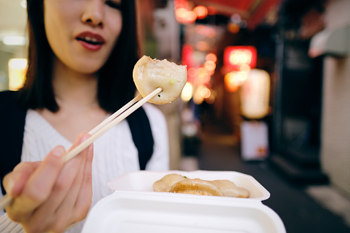 Woman eating take-out food on Izakaya street in Kichijoji, Tokyo, Japan