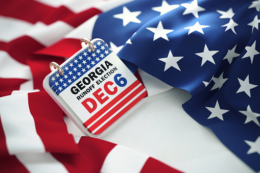 Georgia Runoff Election Dec 6 written calendar over rippled American flag. High angle view and horizontal composition.