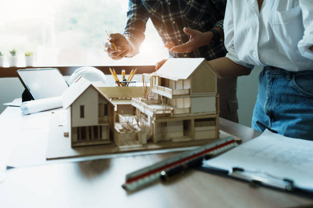 istock Engineers are consulting the team to design an architectural structure for clients with blueprints and building models to work at office 1443432050