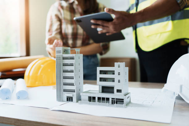 istock Engineers are consulting the team to design an architectural structure for clients with blueprints and building models to work at office 1443433040