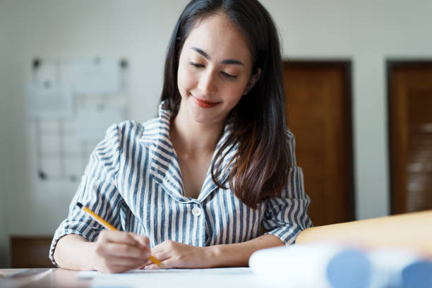istock Portrait of an Asian female engineers are designing house structures and architectural using blueprints, rulers, pencils, dividers and building models to work 1443434160