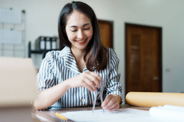 istock Portrait of an Asian female engineers are designing house structures and architectural using blueprints, rulers, pencils, dividers and building models to work 1443434194