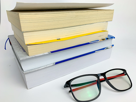 pile of books and glasses on a white background