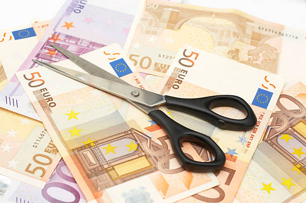 reduzir os custos - cutting currency scissors home finances - fotografias e filmes do acervo