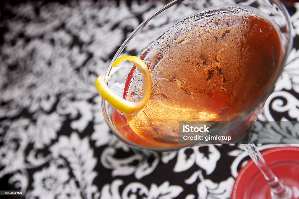 Happy Hour! A cocktail on a tabletop with red coaster, lemon twist and patterned modern background After Work Stock Photo