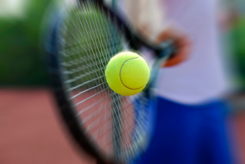 Close-up with black background of focused attractive young adult female tennis player prepared to return the ball. Waist up with copy space