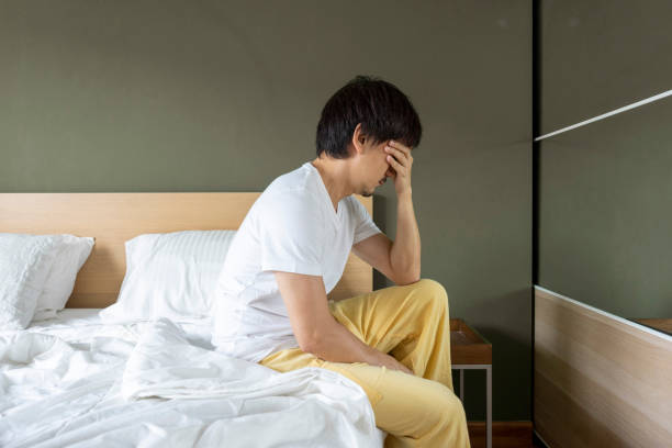 istock Depressed Asian man sitting in bed cannot sleep. 1443440038